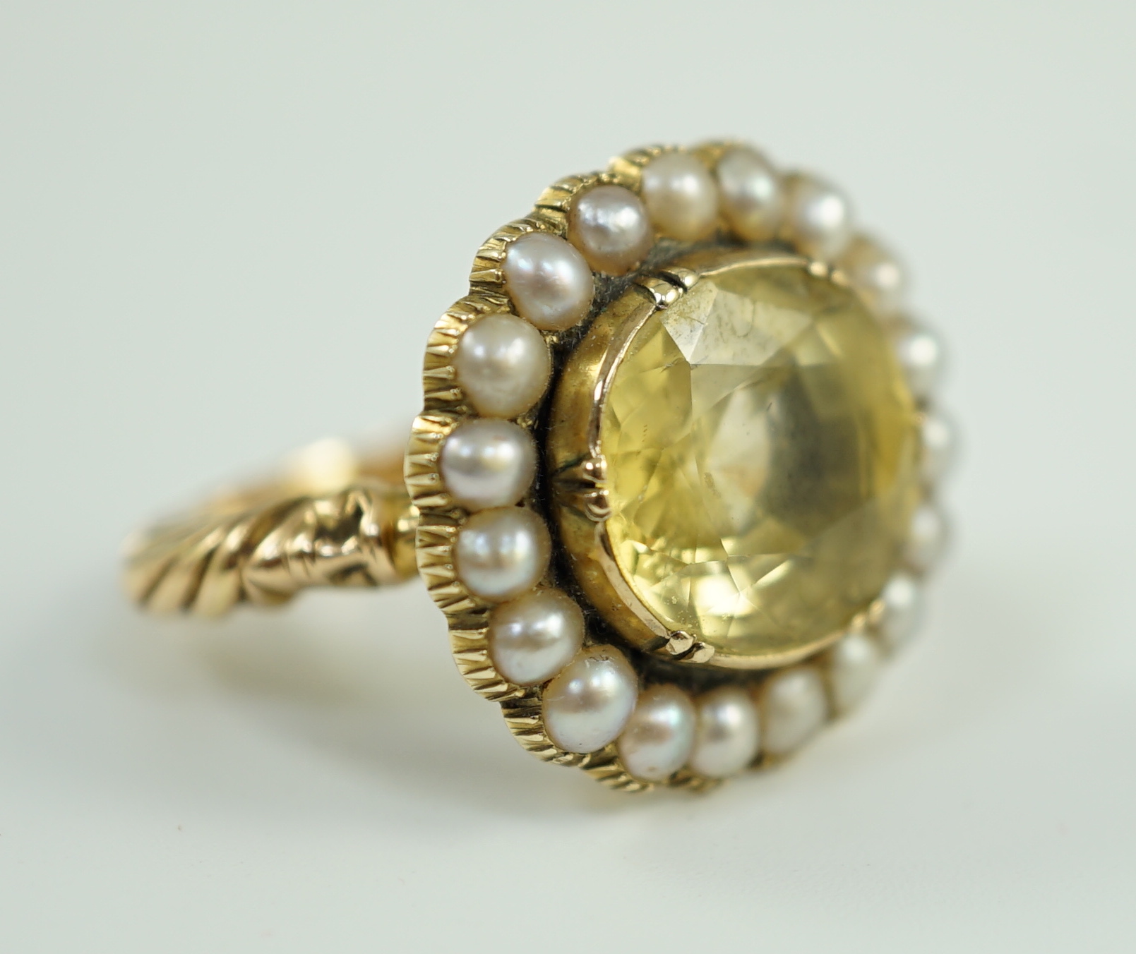 A 19th century style gold and round cut single stone yellow sapphire set dress ring, with split pearl set border